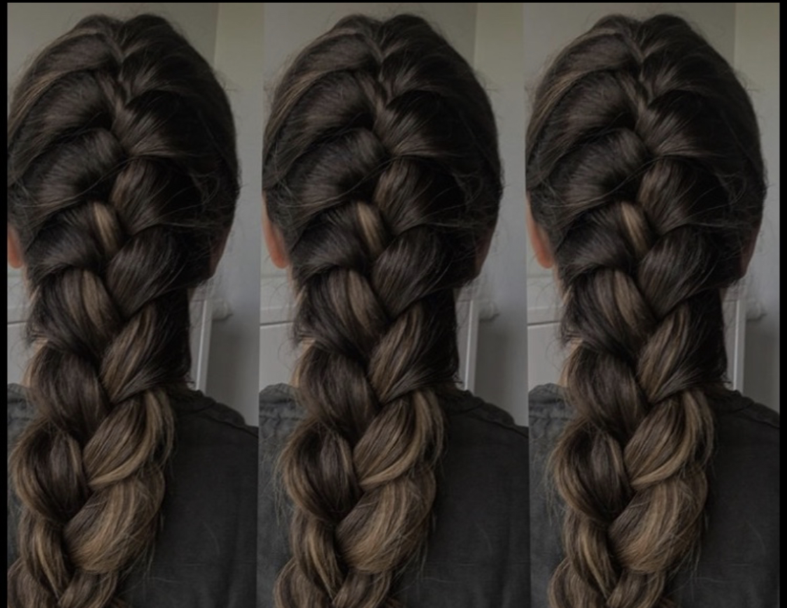 Długi, gęsty warkocz francuski z ciemnych włosów z pasemkami w odcieniach blondu, widoczny od tyłu na tle jasnych drzwi.