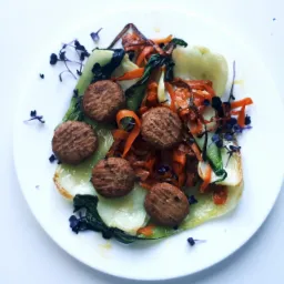 Elegancko podane danie wegetariańskie na białym talerzu: kotleciki roślinne, podsmażany pak choi, marchewka julienne i mikro zioła.