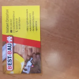 Wizytówka firmy budowlanej Best-Bau z narzędziami, logo i danymi kontaktowymi na drewnianym tle. Oferta: roboty ogólnobudowlane, wykończenia wnętrz, docieplenia, ogrodzenia.