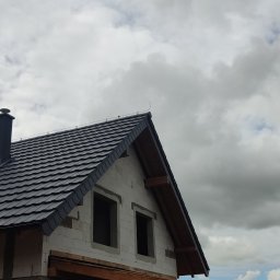 TOMASZ TOMCZAK TOM-BUD - Nowy, grafitowy dach z blachodachówki na domu w trakcie budowy, widoczne okna poddasza i komin, pochmurne niebo.