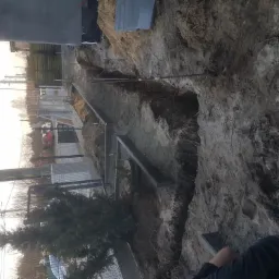 Wykop pod fundamenty z widocznym zbrojeniem i deskowaniem, przygotowany do zalania betonem, obok rosnąca zielona choinka.