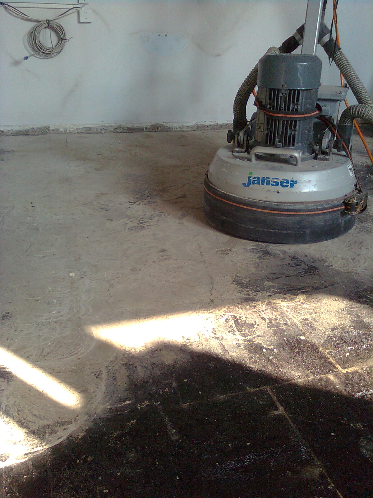 Szlifowanie parkietu w Kraśniku za pomocą maszyny JanSer, widoczne ślady po szlifowaniu, pył i nierówności na podłodze.