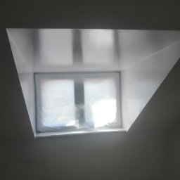 SF-Wykończenia Wnętrz (Quality) - Świeżo pomalowane poddasze ze skośnym oknem zabezpieczonym folią malarską, widoczne niedoskonałości w strukturze ściany przed oknem.