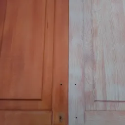 Drewniane drzwi po lewej stronie pomalowane na brązowo, po prawej surowe drewno z widocznym usłojeniem, ukazujące różnicę przed i po renowacji.