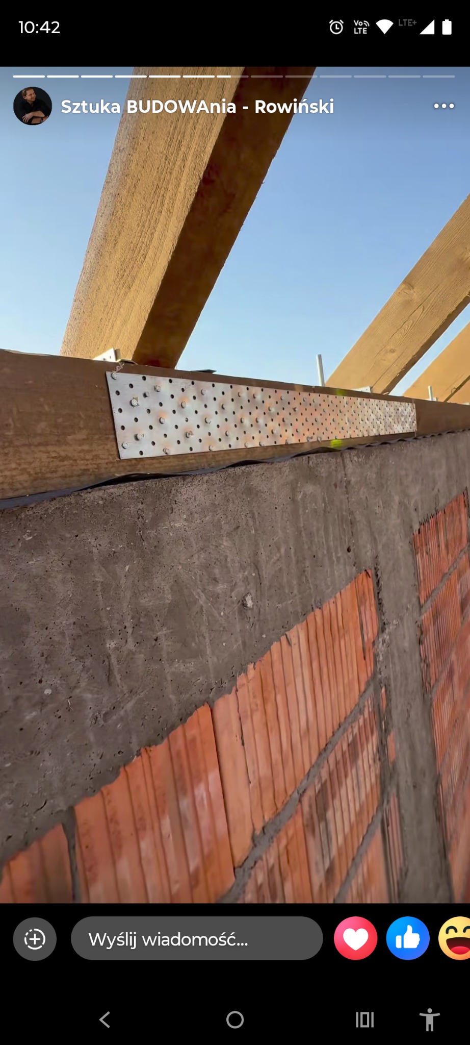 Wiązanie krokwi z murem za pomocą blachy perforowanej. Widoczne elementy konstrukcji dachu i fragment murowanej ściany. Ujęcie z dołu, w tle błękitne niebo.