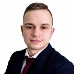 Portret młodego mężczyzny w ciemnym garniturze i bordowym krawacie na białym tle, sugerujący reprezentanta firmy leasingowej.