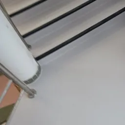 Szare schody z metalową barierką, widok z góry, fragment mozaiki pod barierką.