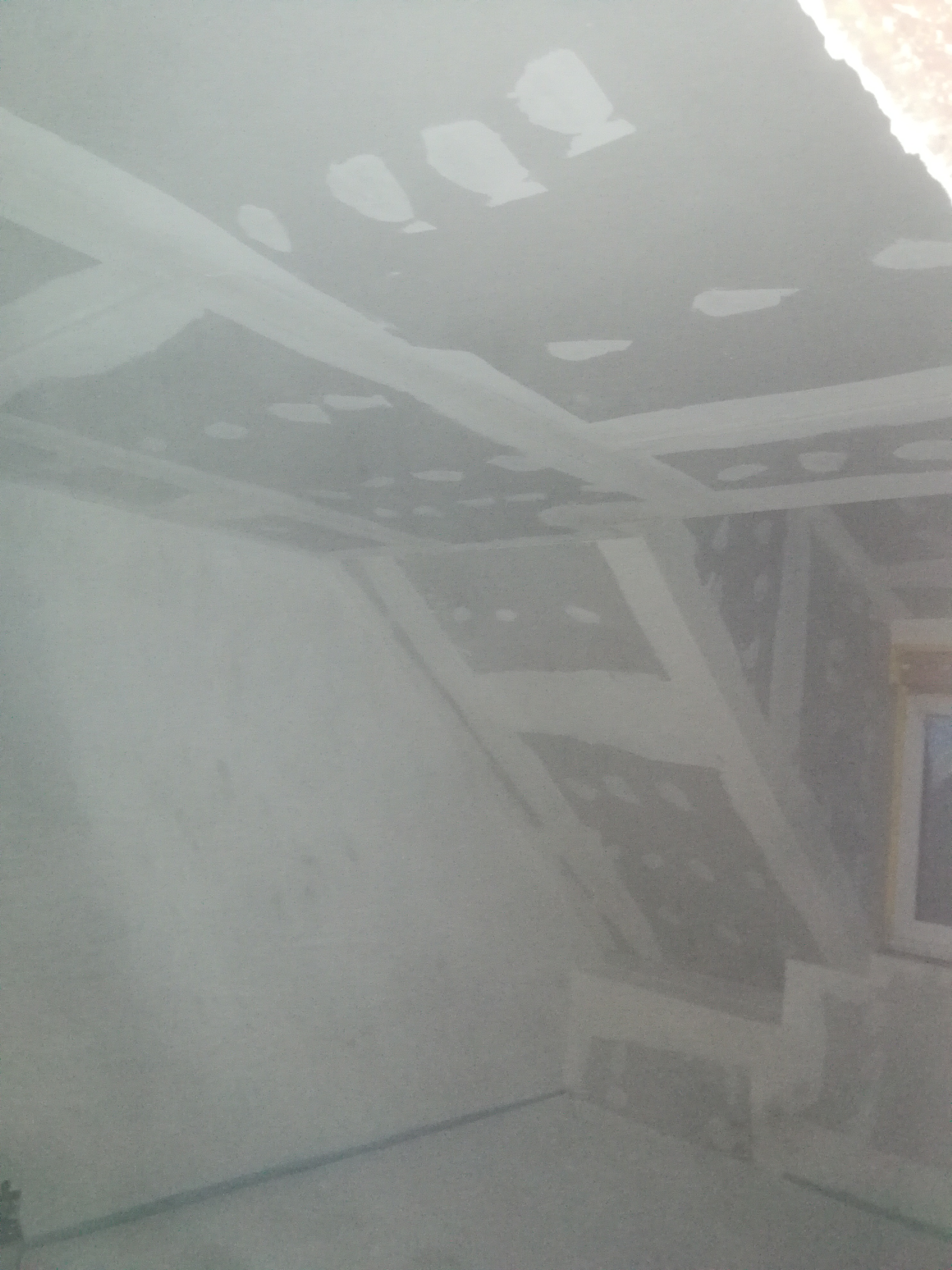 Poddasze w trakcie prac wykończeniowych, widoczne łączenia płyt kartonowo-gipsowych wzmocnione taśmą i pokryte szpachlą, przygotowane do dalszych prac.