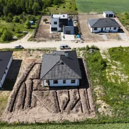 Nowy dom z instalacją podziemną w wykopach, widok z lotu ptaka, sąsiednie domy w tle.