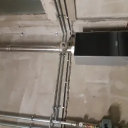 Nowoczesny piec grzewczy marki Buderus zamontowany na surowej ścianie, widoczne rury instalacji grzewczej oraz elementy armatury.