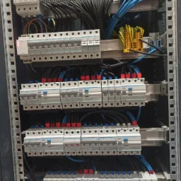 Rozdzielnica elektryczna z zabezpieczeniami i okablowaniem w Lniska, widok z bliska na zainstalowane moduły i przewody.