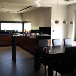 Nowoczesna kuchnia z wyspą i drewnianymi frontami szafek, połączona z jadalnią, widok z perspektywy stołu z filiżanką i okularami.