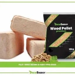 Stos trzech brykietów drzewnych obok czarnego worka z pelletem drzewnym premium, z widocznym logiem producenta i informacją o wadze 15kg, z dodatkową kupką pelletu i zielonym listkiem na pierwszym...