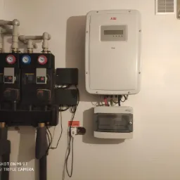 Węzeł cieplny z dwoma pompami obiegowymi Wilo, biały inwerter ABB Trio oraz skrzynka elektryczna ETI zamontowane na białej ścianie w miejscowości Granice.