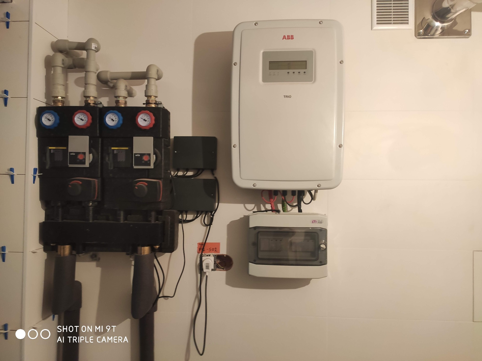 Węzeł cieplny z dwoma pompami obiegowymi Wilo, biały inwerter ABB Trio oraz skrzynka elektryczna ETI zamontowane na białej ścianie w miejscowości Granice.