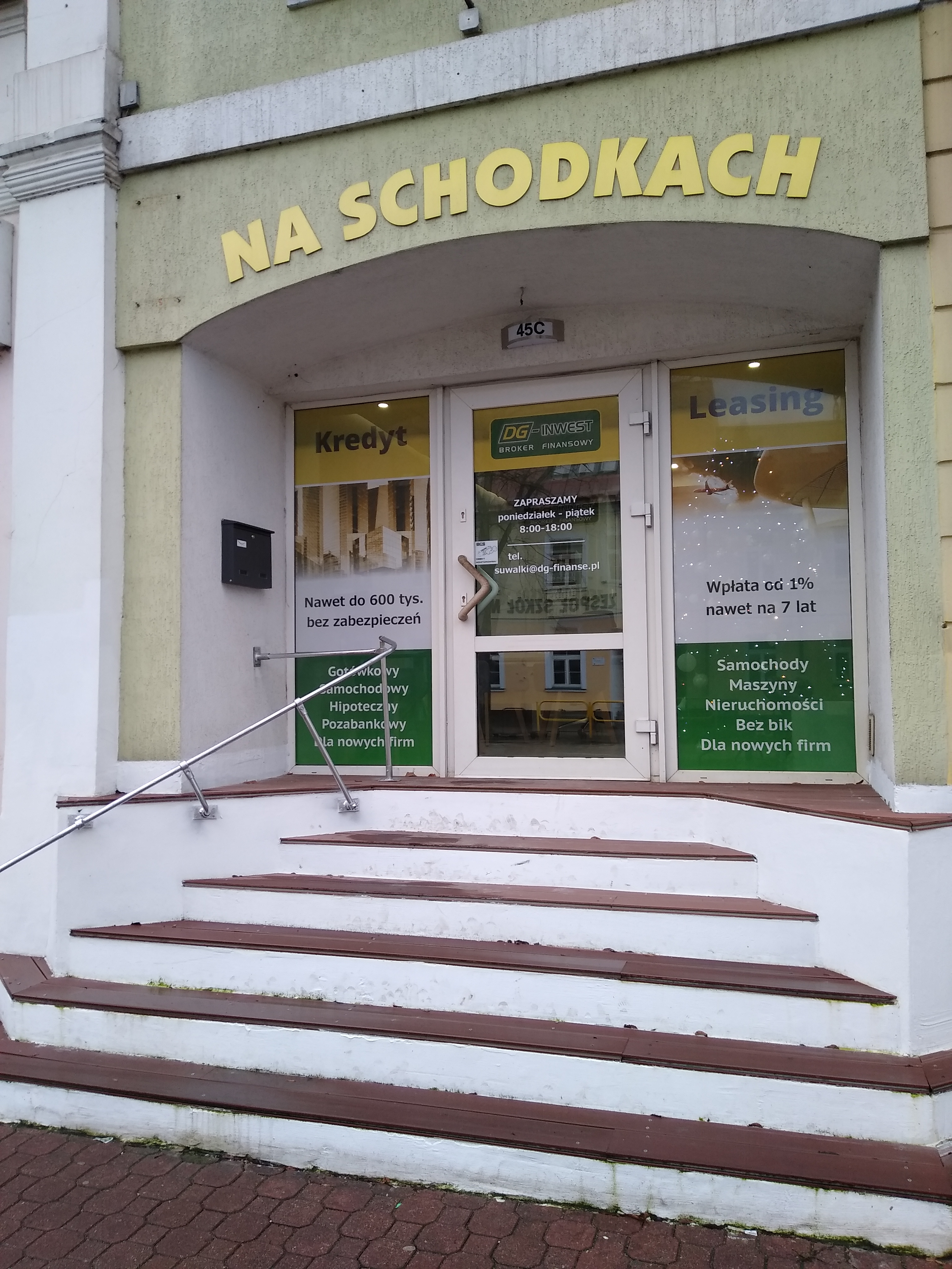 Wejście do biura firmy finansowej 'Na Schodkach' z ofertą kredytów i leasingu, widoczne schody z metalową barierką, na szybach reklamy usług finansowych, adres 45C.
