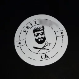 Szablon z wyciętym laserowo logo salonu fryzjerskiego przedstawiającego brodatego mężczyznę w okularach, nożyczki i brzytwę na czarnym tle.