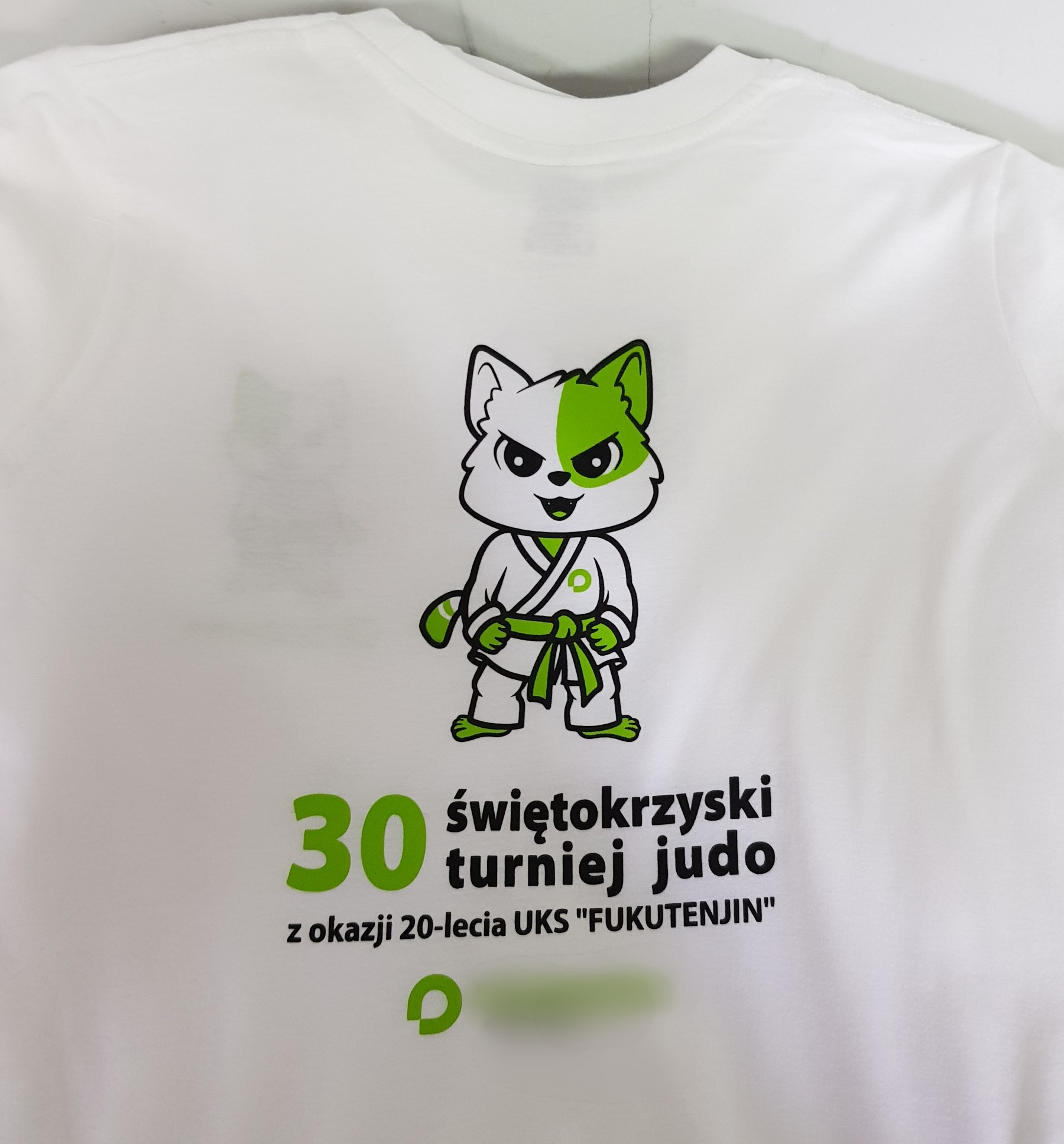 Biała koszulka z nadrukiem zielono-białego lisa w stroju do judo, z napisem '30 świętokrzyski turniej judo z okazji 20-lecia UKS FUKUTENJIN'.