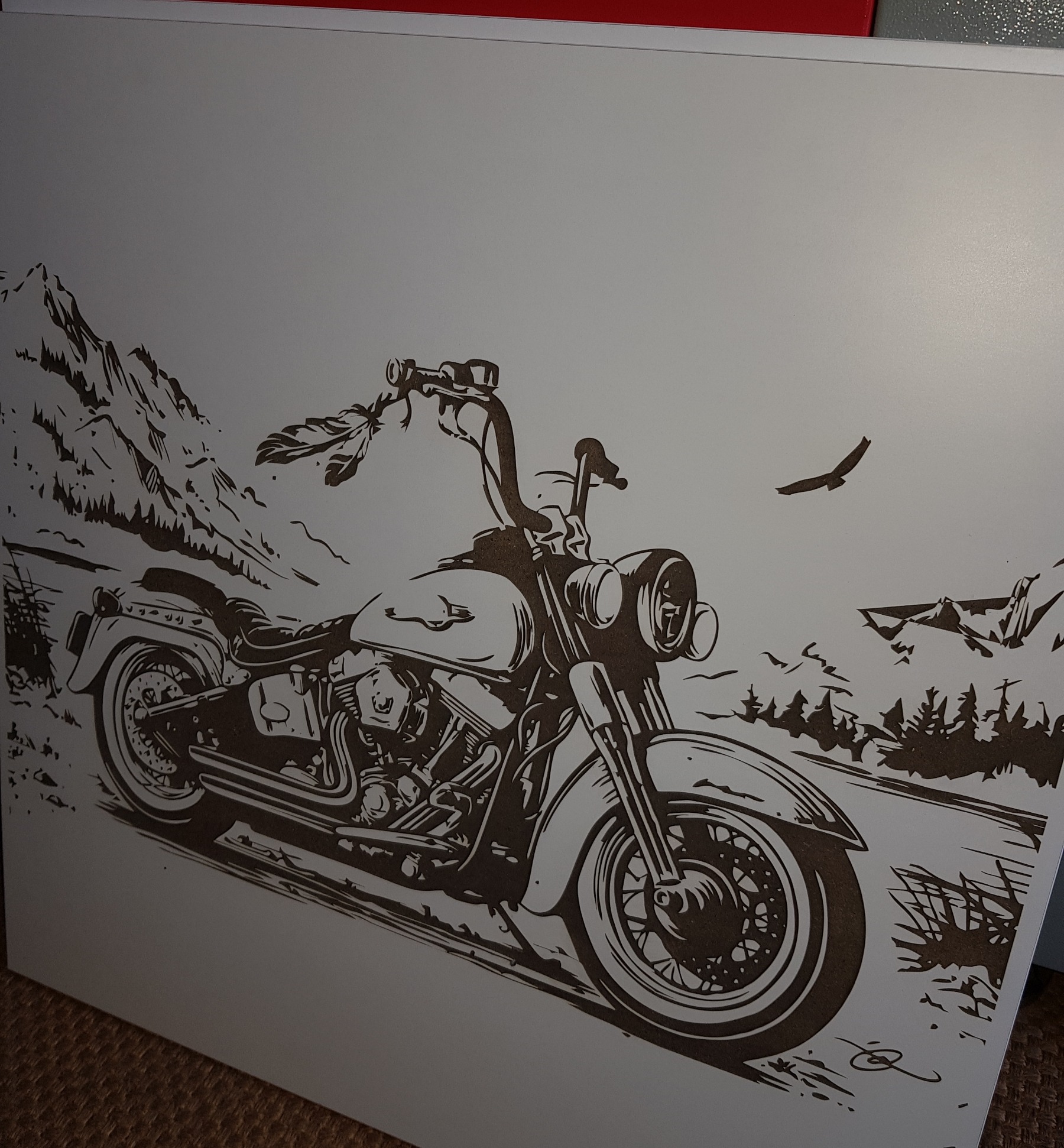 Grafika przedstawiająca motocykl typu chopper na tle górskiego krajobrazu z lecącym ptakiem, wykonana w technice imitującej laserowe grawerowanie na jasnym podłożu.