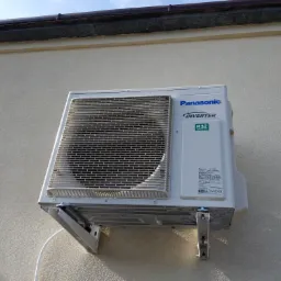 Zewnętrzna jednostka klimatyzacji Panasonic Inverter R32 zamontowana na elewacji budynku, widoczne metalowe wsporniki i przewody.