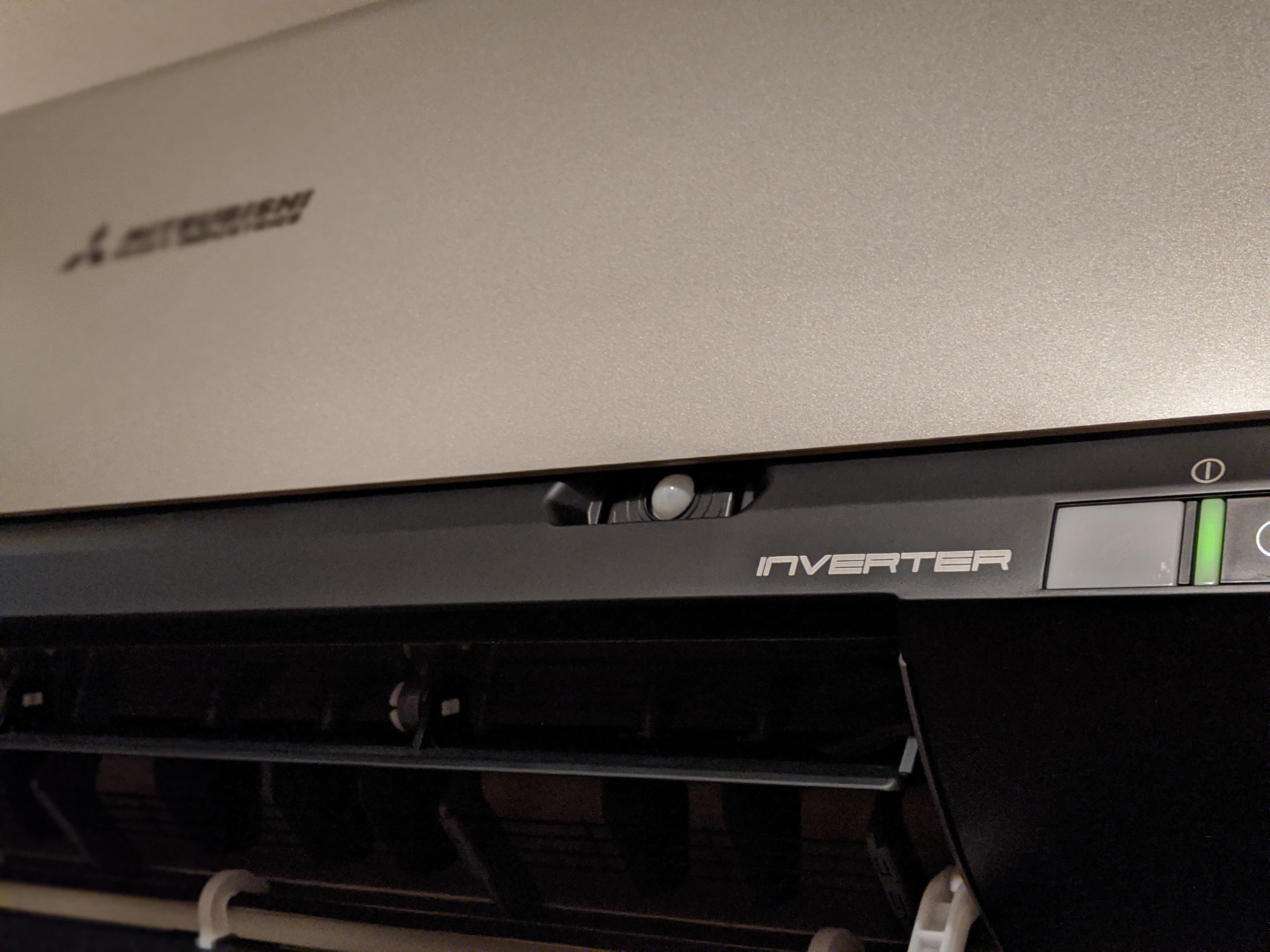 Szczegółowy widok klimatyzatora Mitsubishi Inverter z widocznym panelem sterowania i kratką wylotową powietrza.