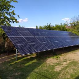 ARCHIGON Sp. z o.o. - Instalacja paneli słonecznych na metalowej konstrukcji, widok z boku, w tle zieleń drzew i błękitne niebo.