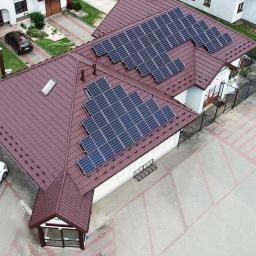 ARCHIGON Sp. z o.o. - Widok z góry na budynek z brązowym dachem pokrytym panelami słonecznymi, z widocznymi samochodami na parkingu.