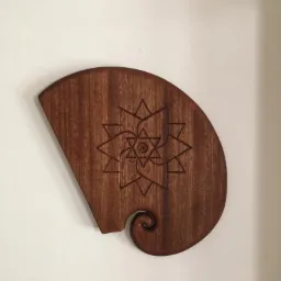Dekoracyjny panel z ciemnego drewna z wygrawerowanym geometrycznym wzorem kwiatowym, przymocowany do białej ściany.