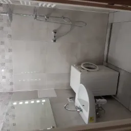 Wykończona łazienka z szarymi płytkami, kabiną prysznicową z deszczownicą, umywalką i pralką.