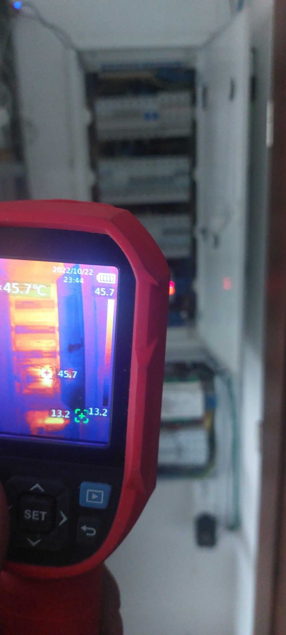 Termowizja rozdzielnicy elektrycznej, widoczne temperatury na wyświetlaczu urządzenia pomiarowego.