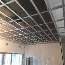 Kdkm - Metalowy stelaż sufitowy, widoczne płyty izolacyjne, przygotowanie do montażu okładziny, ściany w trakcie wykończenia.