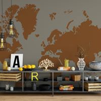 Szara ściana z brązową mapą świata, pod nią niski metalowy regał z dekoracjami: drewniane skrzynki, owoce, litery A i R, ozdobne drzewko, wazony i lampy wiszące w stylu industrialnym.