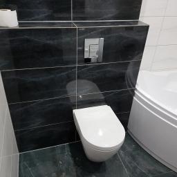 Arkadiusz Jurkowski - Nowoczesna łazienka z czarno-białymi płytkami marmurkowymi, podwieszaną miską WC z chromowanym przyciskiem spłukującym i narożną wanną.