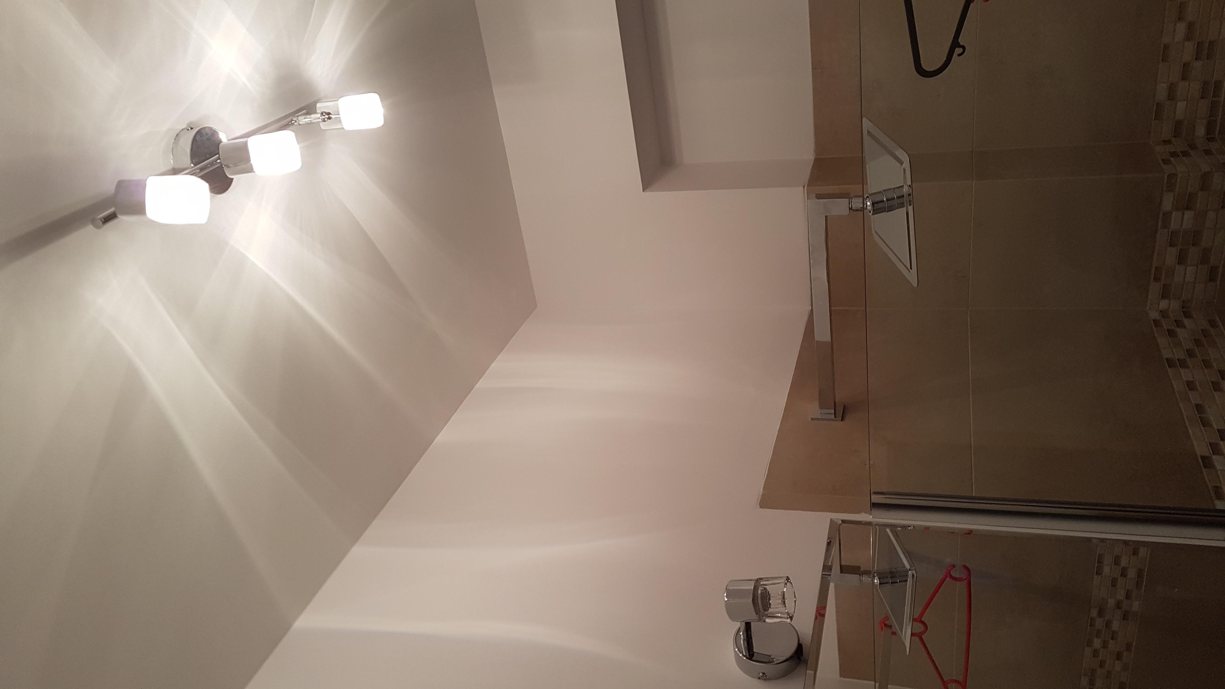 Nowoczesna łazienka z chromowaną armaturą, oświetleniem LED i kabiną prysznicową z dekoracyjną mozaiką.