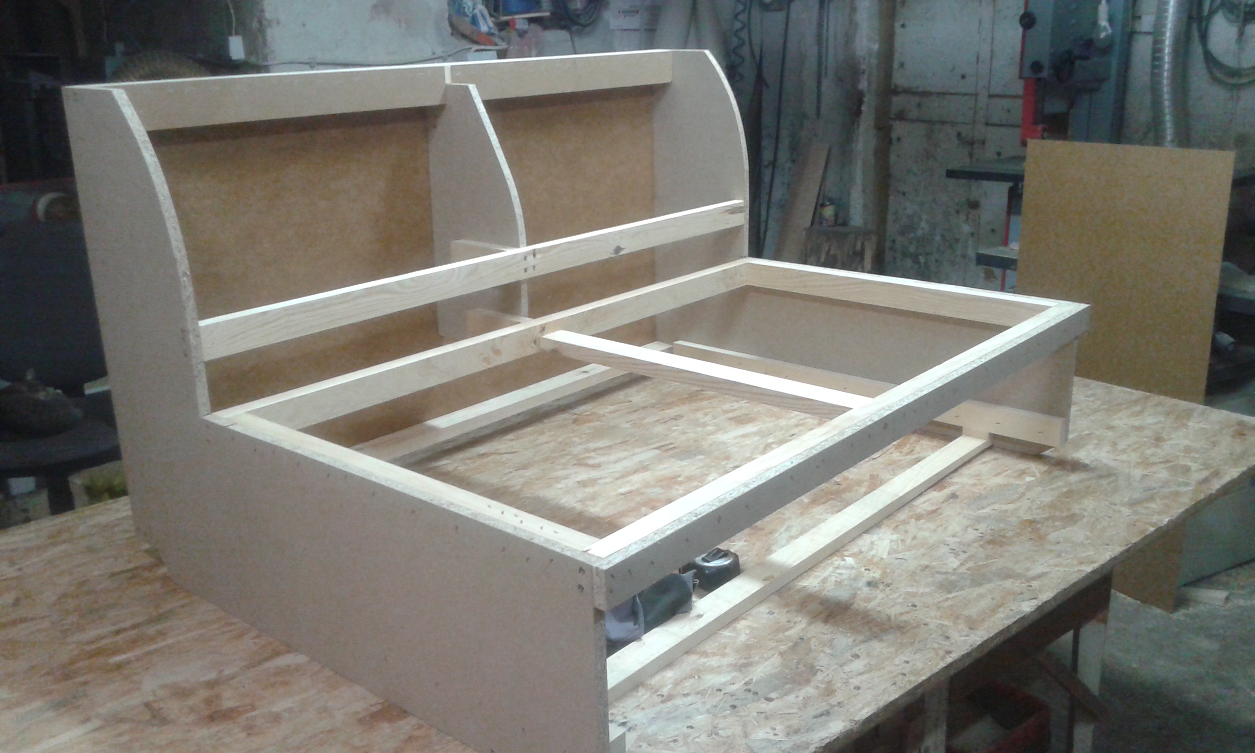 Konstrukcja drewniana antresoli w trakcie budowy, widoczne elementy ramy i płyty MDF, narzędzia pomiarowe w tle warsztat.