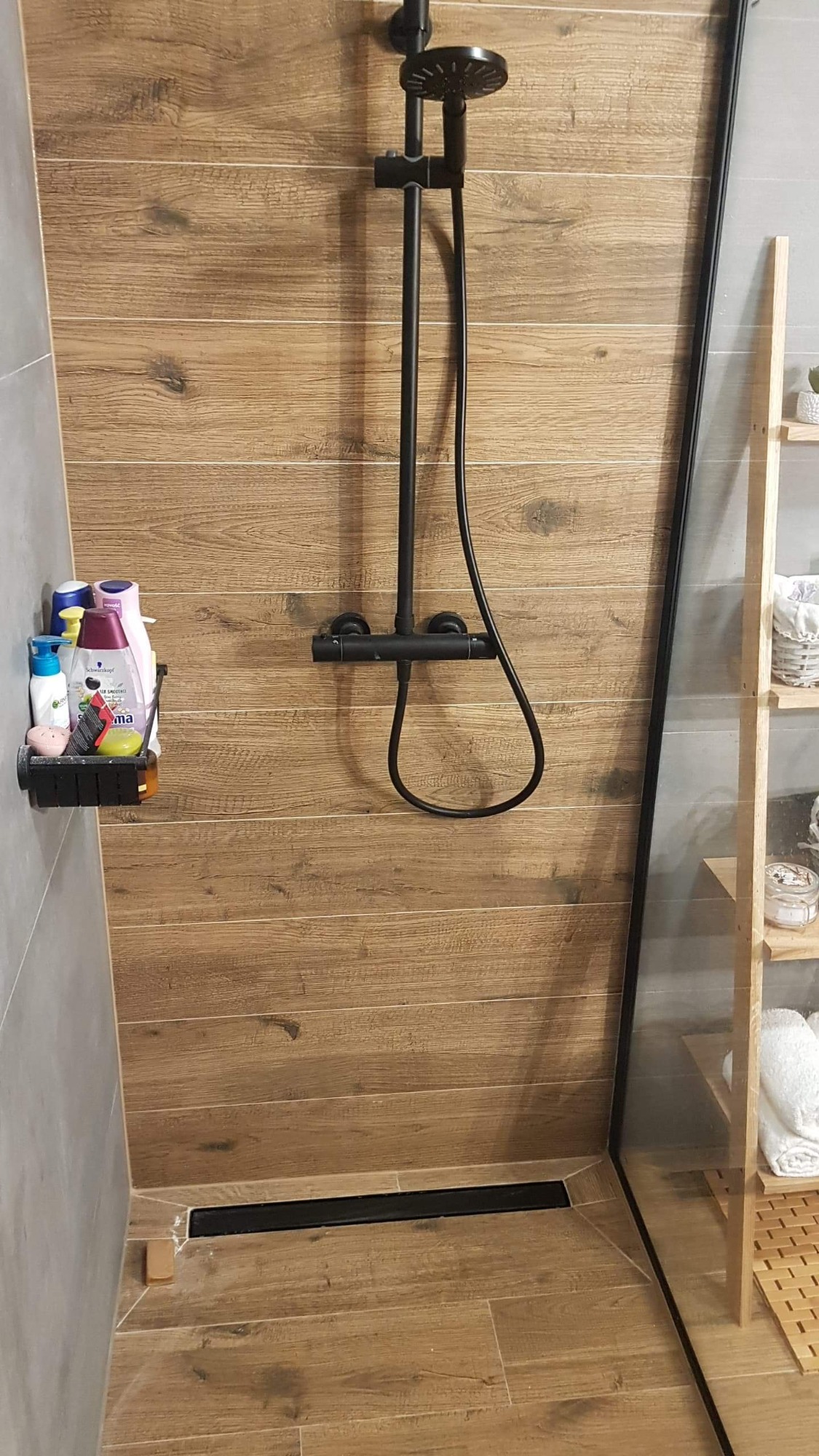 Kabina prysznicowa z deszczownicą i odpływem liniowym, wykończona płytkami imitującymi drewno, widok z Pruszcza Gdańskiego.