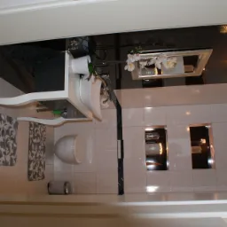 Elegancka łazienka z czarno-białymi płytkami, podwieszaną toaletą, umywalką z szafką w stylu retro, lustrem z kwiatami i nowoczesnym oświetleniem.