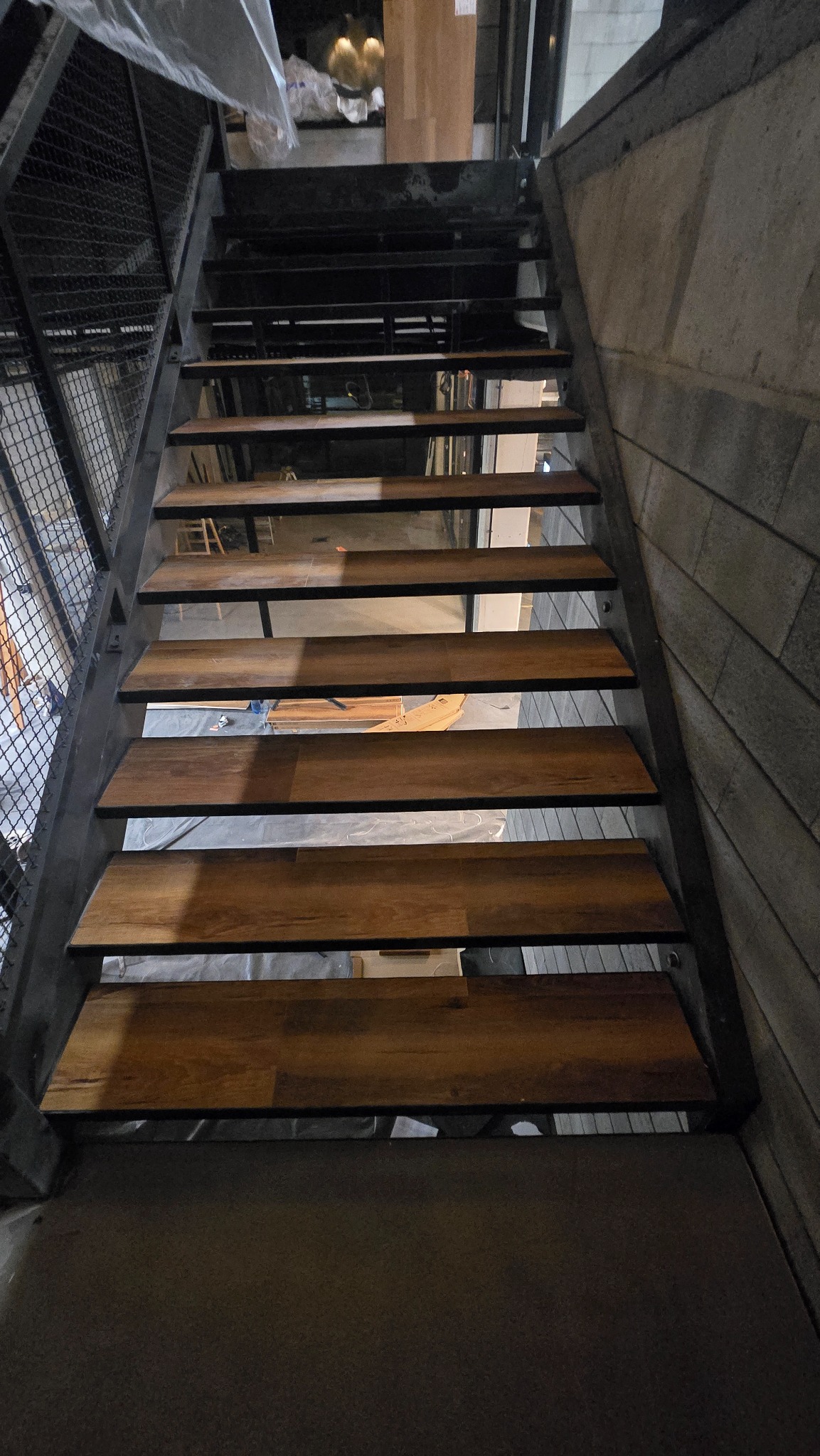 Schody z drewnianymi stopniami i metalową konstrukcją w Grabowie nad Pilicą. Widok z dołu, ukazujący detale wykończenia i nowoczesny design.