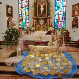 Beata Borgus BB Florist Pracownia Florystyczna Beata Borgus - Dekoracja w kościele z okazji uroczystości, centralnie umieszczona drewniana łódka wypełniona złotymi rybkami z imionami, w tle ołtarz i witraże.