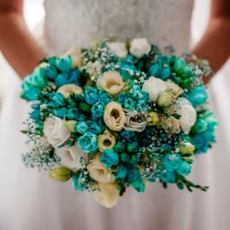 Beata Borgus BB Florist Pracownia Florystyczna Beata Borgus - Panna młoda trzymająca bukiet ślubny z białych róż i turkusowych tulipanów, uzupełniony drobnymi białymi kwiatami gipsówki.