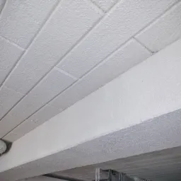 Pomalowany na biało strop z betonowych płyt kanałowych z widocznym żebrem konstrukcyjnym, wykończony natryskowo.