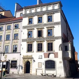 Fasada odrestaurowanej, zabytkowej kamienicy z dekoracjami sgraffito, widok z poziomu ulicy w słoneczny dzień.