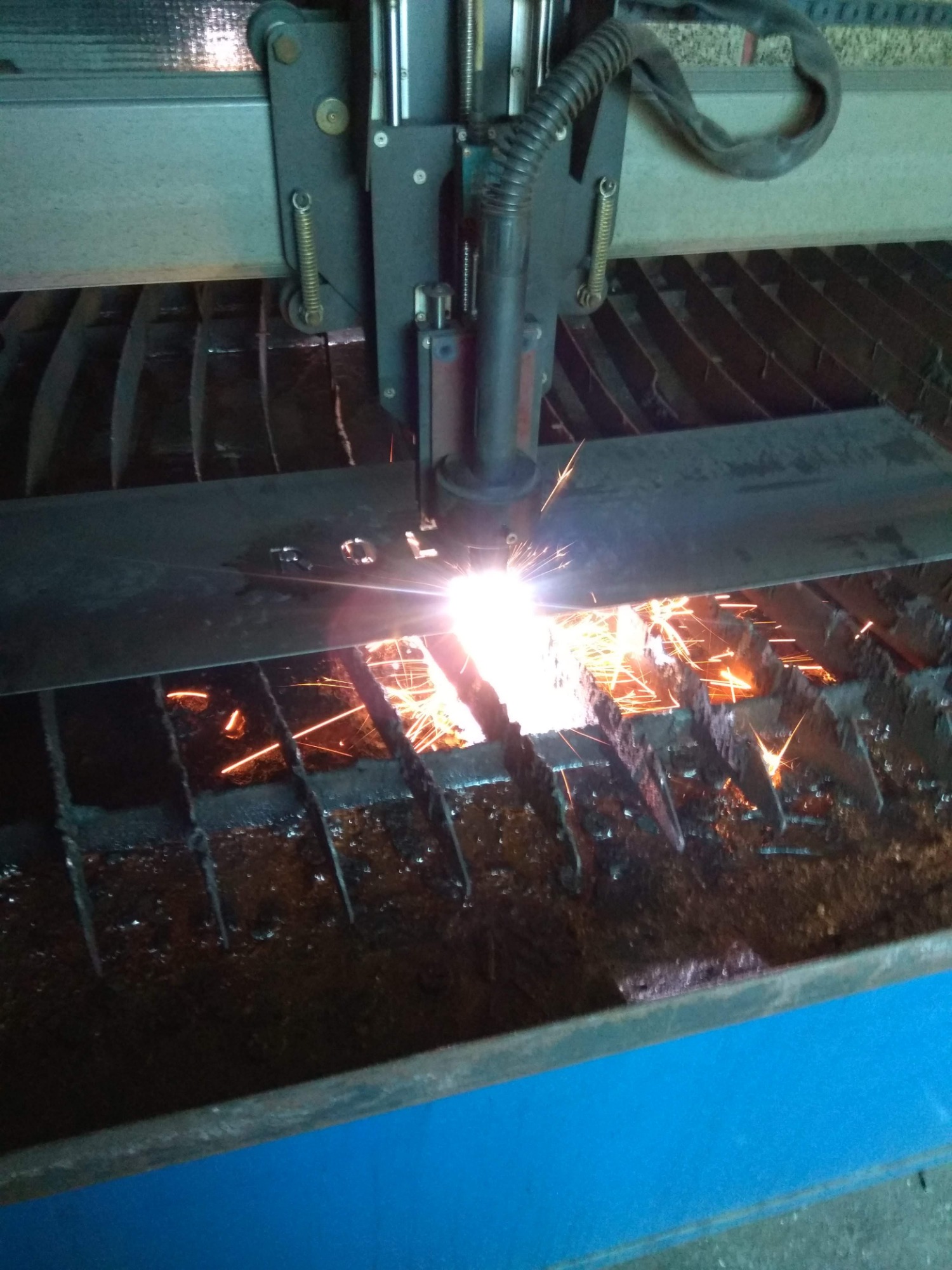 Cięcie metalu plazmą: iskry i roztopiony metal podczas obróbki blachy na stole roboczym.