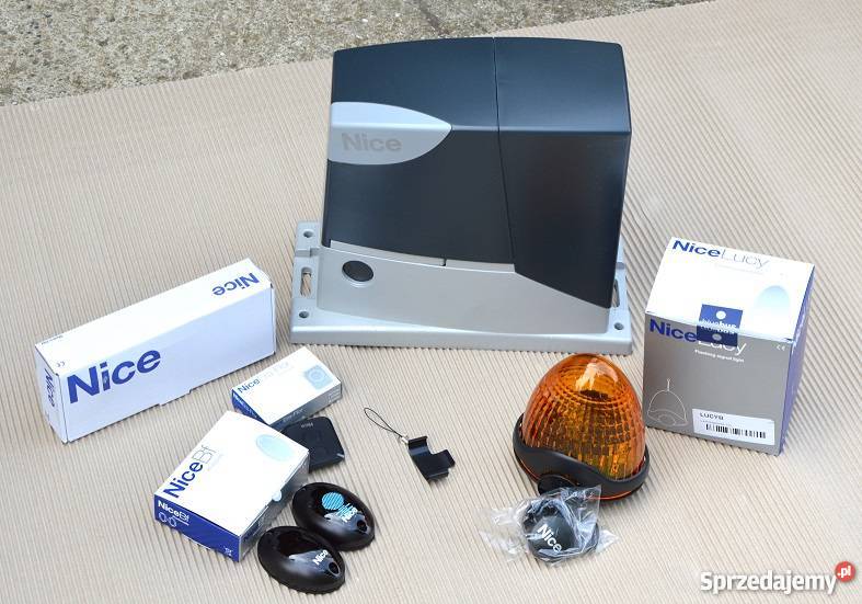 Zestaw komponentów do automatyki bram marki Nice: napęd, piloty, lampa ostrzegawcza i akcesoria w oryginalnych opakowaniach na neutralnym tle.