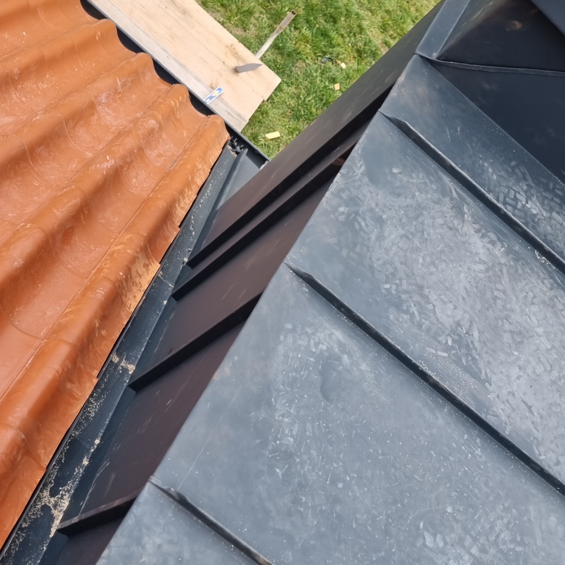 Fragment dachu w Środzie Śląskiej, gdzie połączono starą dachówkę ceramiczną z nowym pokryciem z blachy na rąbek stojący w kolorze grafitowym.