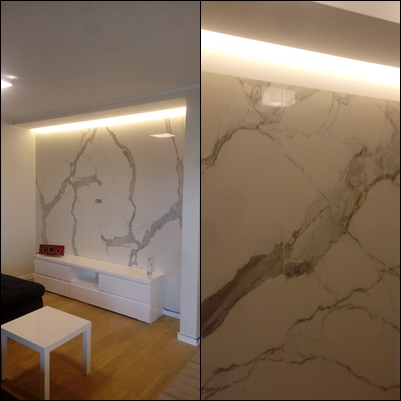 Ściana w salonie w Kępnie wyłożona wielkoformatowymi płytami imitującymi marmur z podświetleniem LED, tworząca efektowną dekorację za telewizorem.