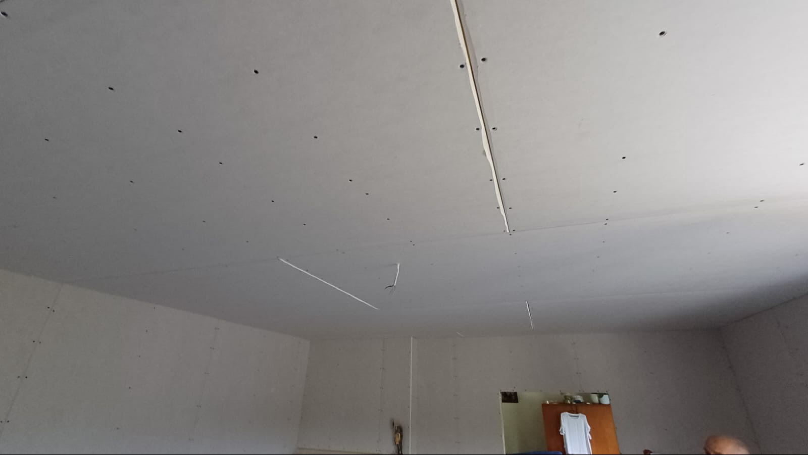 Montaż sufitu podwieszanego z płyt karton gips, widoczne wkręty mocujące i szpachlowane łączenia płyt.