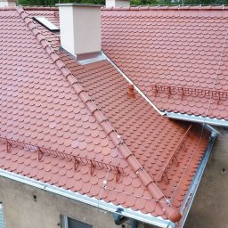 „BUD” Borucki Usługi Dekarskie Piotr Borucki - Czerwony dach z dachówki karpiówki na budynku mieszkalnym, widok z góry. Widoczne kominy, okno dachowe i system odśnieżania.