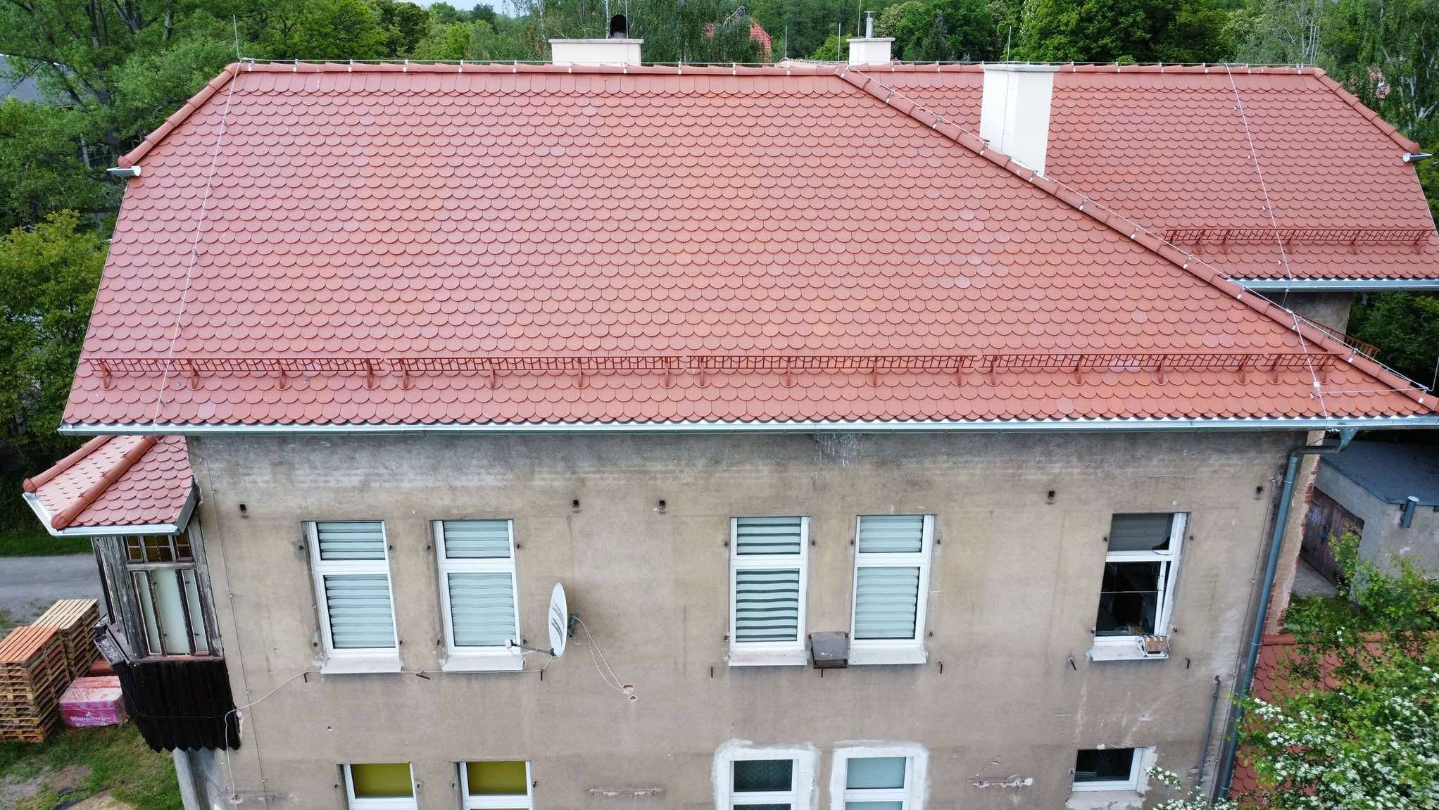 Czerwona dachówka karpiówka na budynku w Uciechowie. Widok z góry ukazuje detale pokrycia i orynnowanie.