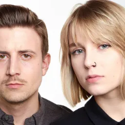 Portret studyjny mężczyzny z lekkim zarostem i kobiety z kolczykiem w nosie na białym tle.